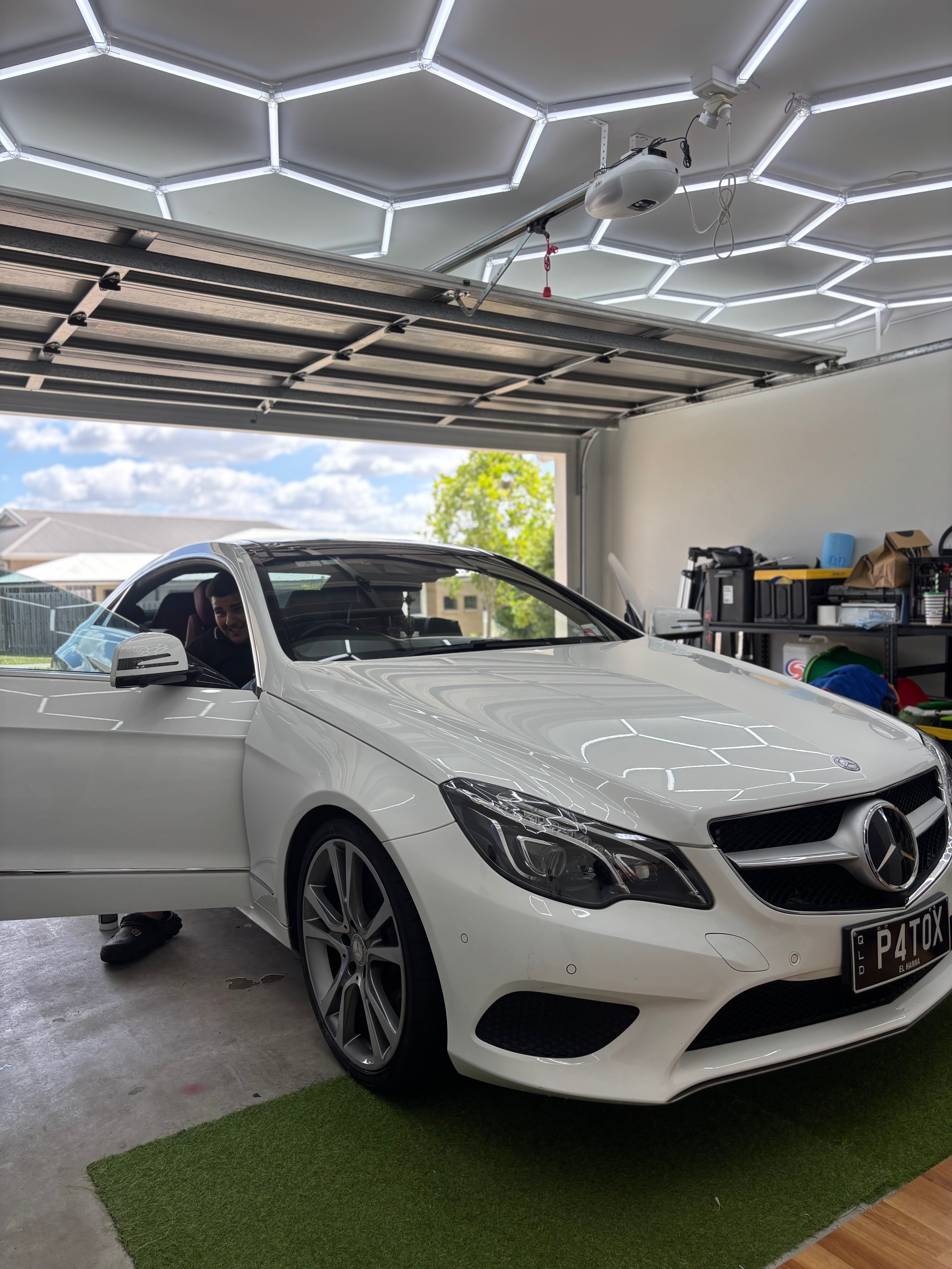 A freshly detailed white Mercedes parked inside a bright, clean garage.