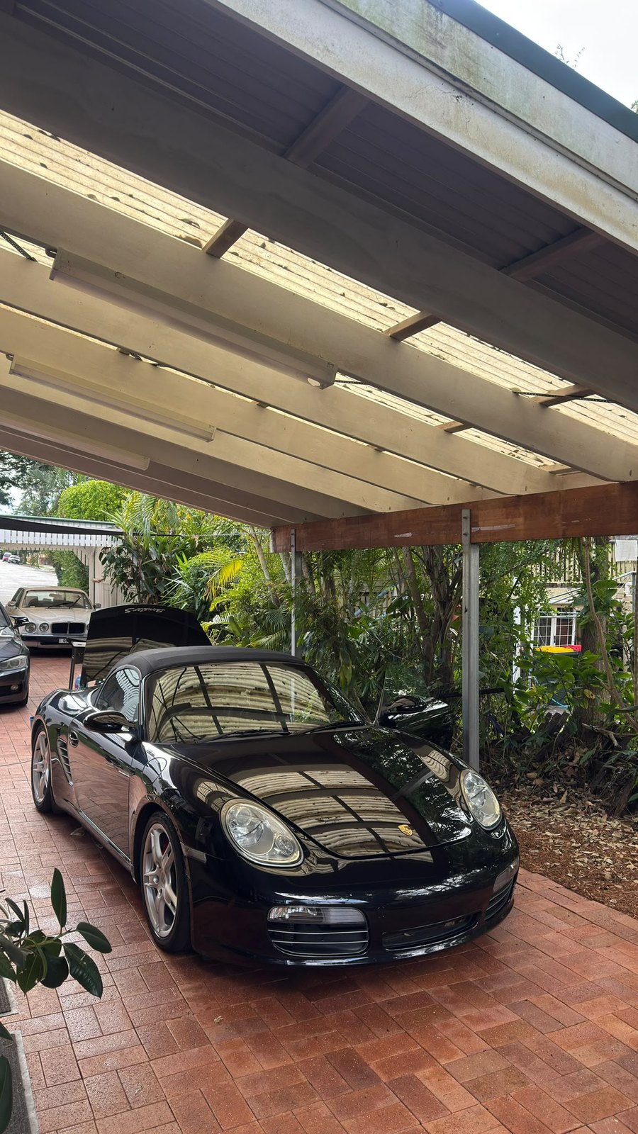 Freshly washed Porsche under a carport, paint reflecting the roofline